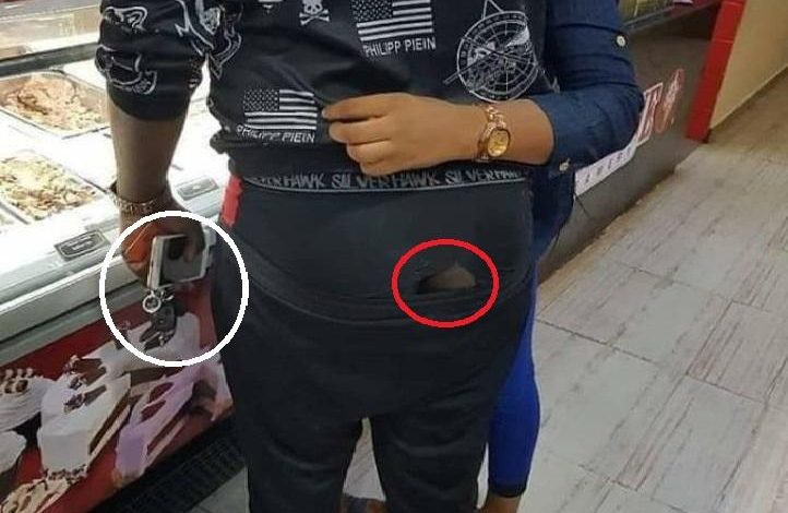 A lady visited Facebook to share the picture of a “love-filled” couple she saw at the Shoprite shopping center in Abuja, Nigeria. The young man holds a car key with iPhone and another smartphone but spotted wearing tore underwear.