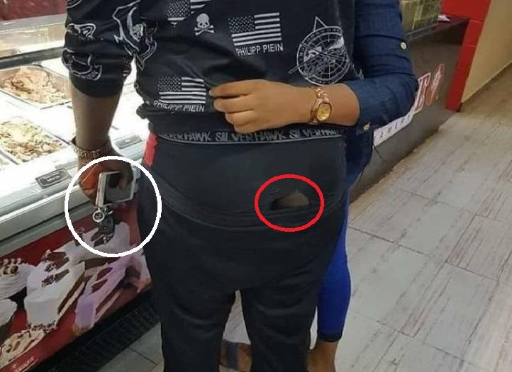 A lady visited Facebook to share the picture of a “love-filled” couple she saw at the Shoprite shopping center in Abuja, Nigeria. The young man holds a car key with iPhone and another smartphone but spotted wearing tore underwear.