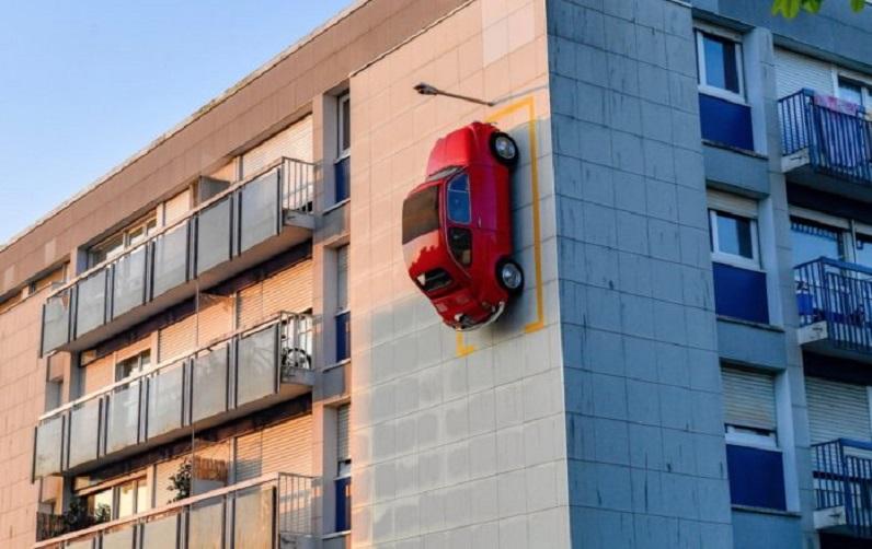 Red Fiat 500 parked on the facade of a building