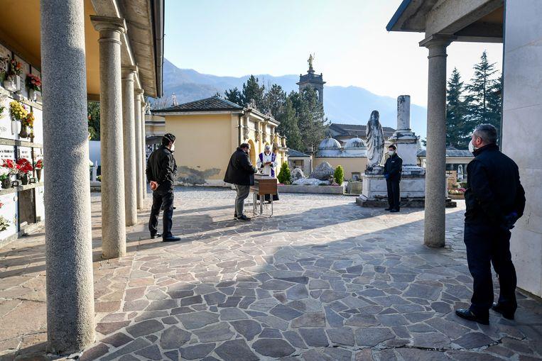 In Zogno, Lombardy, funeral directors and a priest are the only people present at a funeral of a corona victim.