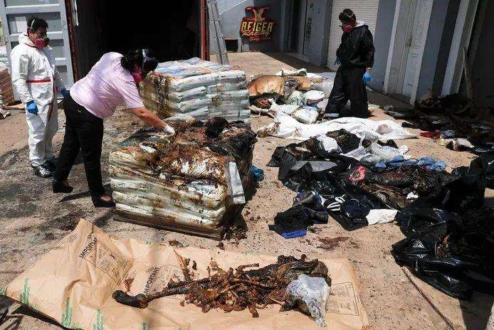 Forensic investigators at the remaining bodies found in the container.