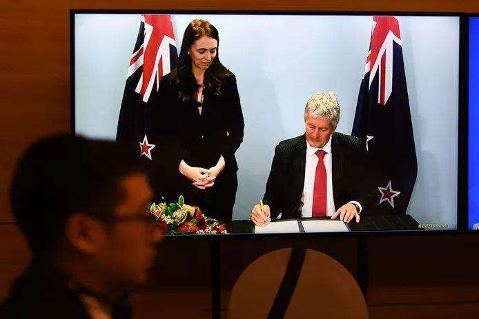New Zealand Prime Minister Jacinda Ardern sees her trade minister, Damien O'Connor, sign his signature.