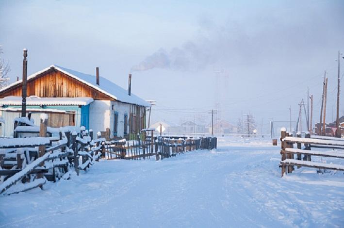 Oymyakon, Sakha Republic, Russia - February 22, 2020: Traditional wooden houses (izba) and smoke from the chimneys, one of the coldest permanently inhabited settlements on Earth, Pole of cold, -48 °C