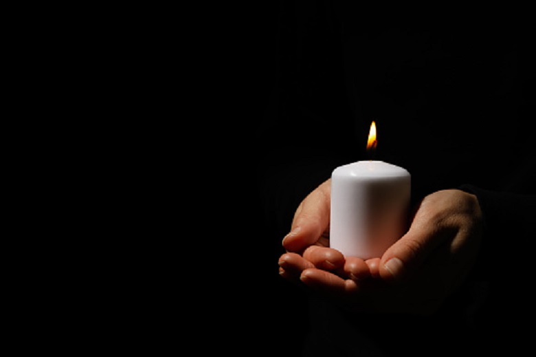 Bride’s eldest relative holds candle on black background