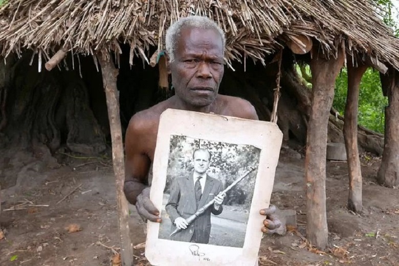 A resident of Tanna shows the photo of Prince Philip posing with the wooden stick the  villagers made for him. (photo from 2017)