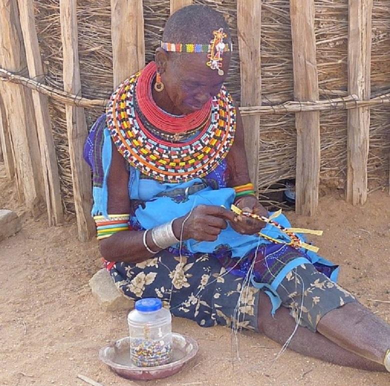 African woman weaves bead souvenirs