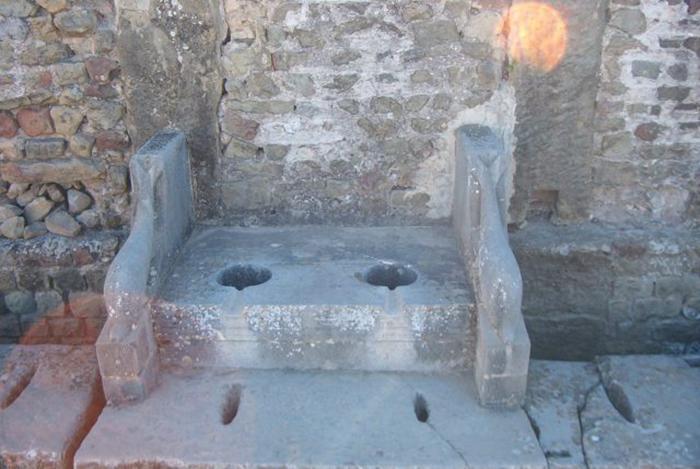 Roman toilet surrounded by sculptures of dolphins